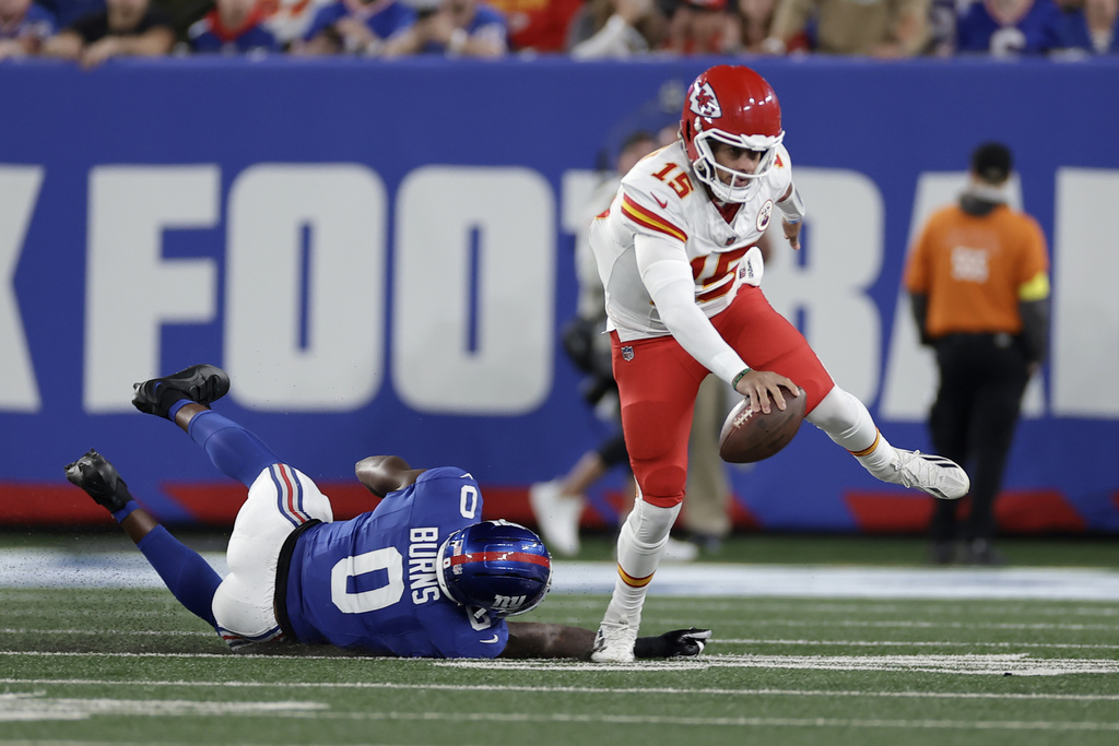 Kansas City Chiefs quarterback Patrick Mahomes (15) scrambles away from New York Giants outside linebacker Brian Burns (0) during the first half of an NFL football game Sunday, Sept. 21, 2025, in East Rutherford, N.J. (AP Photo/Adam Hunger)
