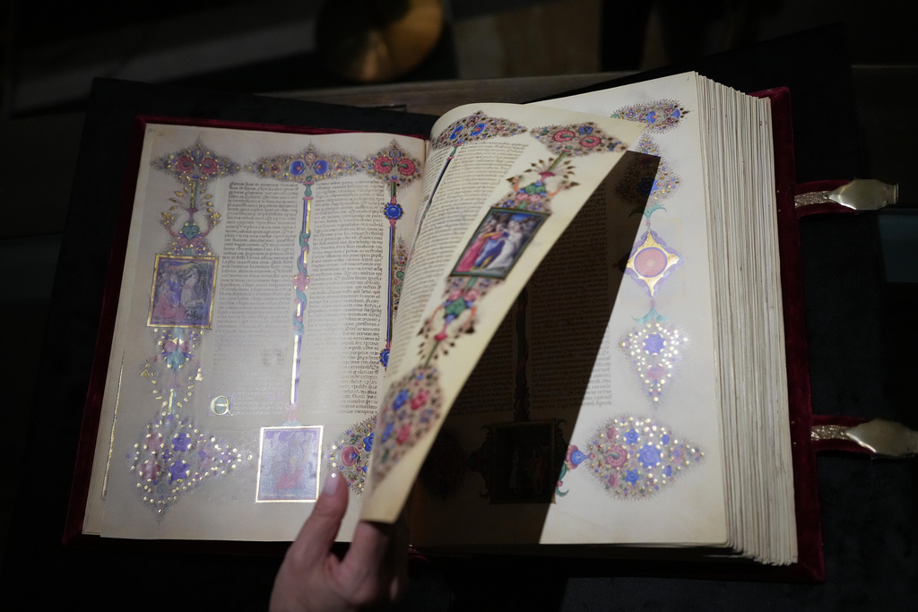 A journalist flips through a faithful reproduction of the 15th century Borso D'Este Bible, comprising two illuminated manuscripts, during its unveiling at the Italian Senate as part of the Vatican's Holy Year celebrations in Rome, Thursday, Nov. 13, 2025. (AP Photo/Alessandra Tarantino)