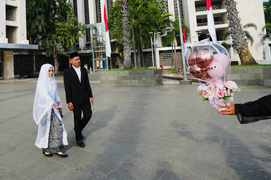 Dafa, second left, and his bride Zulfa arrive to take part in a mass wedding ceremony at Istiqlal Mosque in Jakarta, Indonesia, Wednesday, Dec. 3, 2025. (AP Photo/Tatan Syuflana)