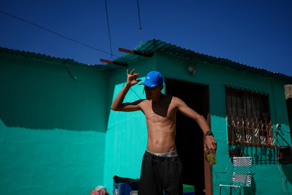 Abraham Castro, a Venezuelan migrant who abandoned the journey with his partner and children to the United States following President Donald Trump's immigration crackdown, dances with a drink in hand during Christmas celebrations in Maracay, Venezuela, Thursday, Dec. 25, 2025. (AP Photo/Matias Delacroix)