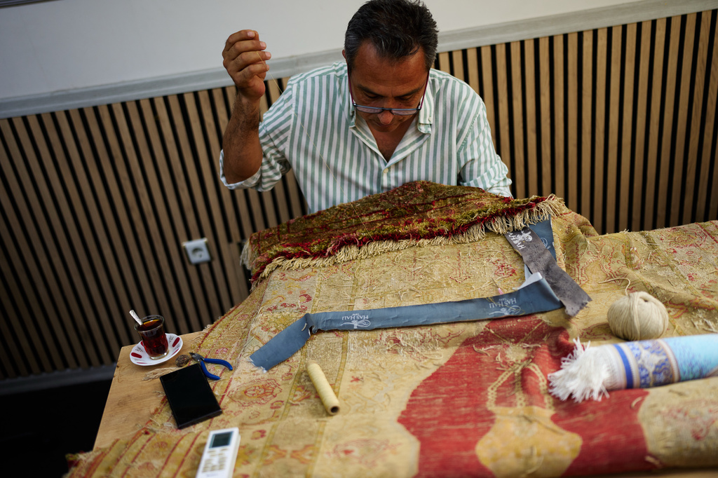 Master carpet restorer Ahmet Bayrakdar works in his workshop near the Sultan Ahmed Mosque in Istanbul, Turkey, Friday, Aug. 7, 2026. (AP Photo/Francisco Seco)