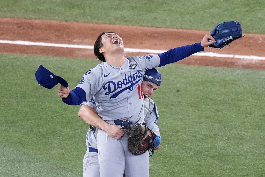 Los Angeles Dodgers pitcher Yoshinobu Yamamoto (18) celebrates with teammate Will Smith after the team defeated the Toronto Blue Jays in Game 7 of baseball's World Series, Sunday, Nov. 2, 2025, in Toronto. (Chris Young/The Canadian Press via AP)