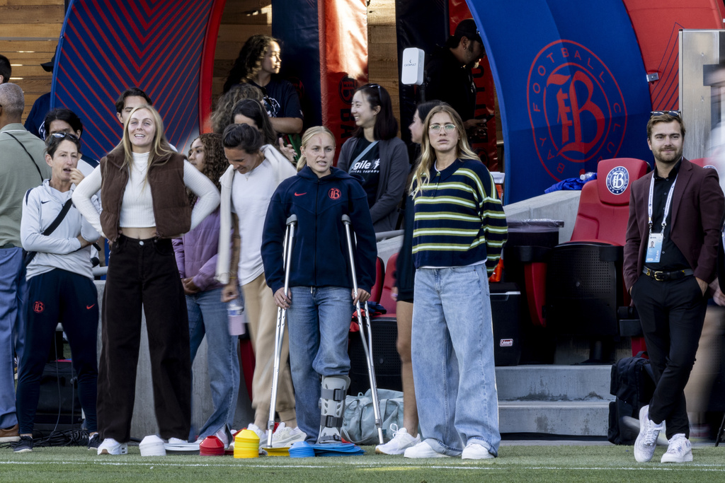 Bay FC forward Penelope Hocking, center on crutches, stands on the sideline before a NWSL soccer match against San Diego Wave FC in San Jose, Calif., Saturday, Aug. 16, 2025. (Stephen Lam/San Francisco Chronicle via AP)
