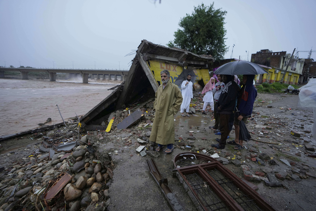 Residents look at the remains of their houses, damaged by flash floods at the banks of Tawi river in Jammu, India, Wednesday, Aug. 27, 2025. (AP Photo/Channi Anand)