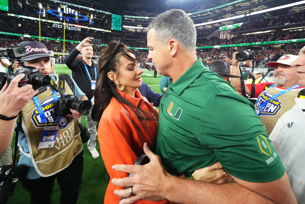 Miami head coach Mario Cristobal, right, talks to his wife, Jessica Cristobal, following the Cotton Bowl College Football Playoff quarterfinal game against Ohio State Wednesday, Dec. 31, 2025, in Arlington, Texas. (AP Photo/Julio Cortez)
