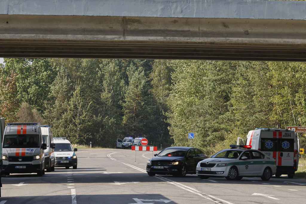 Ambulances and police cars are parked on the road not far from the area of powerful explosions after several rail cars loaded with liquefied gas caught fire in the suburbs of Vilnius, Lithuania, Wednesday, Sept. 10, 2025. (AP Photo/Mindaugas Kulbis)