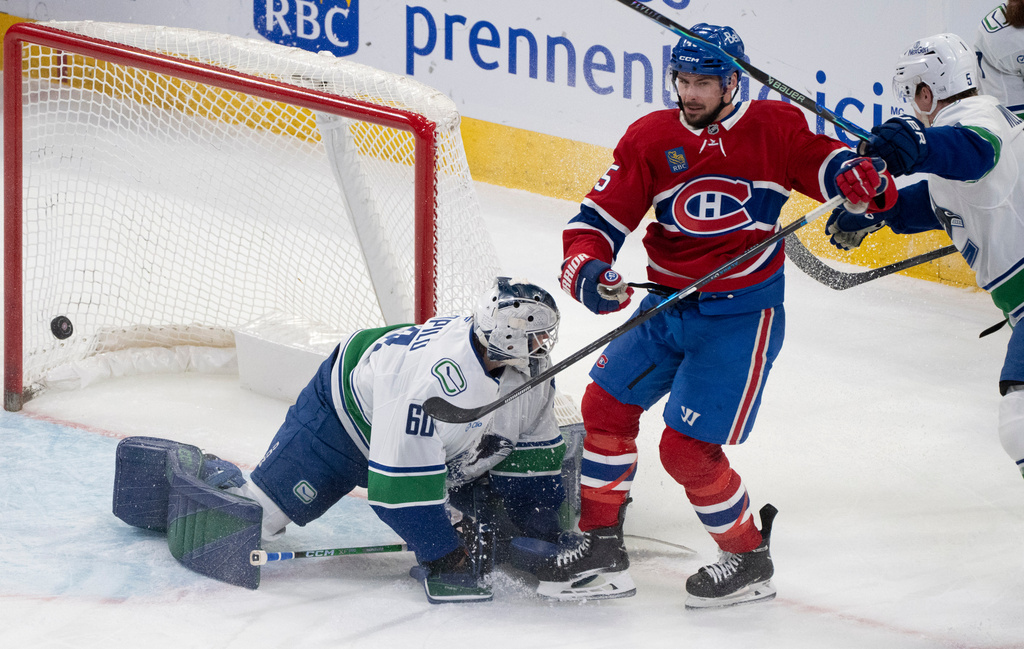 Montreal Canadiens' Alexandre Carrier, second from left, scores against Vancouver Canucks goaltender Nikita Tolopilo (60) as Canucks' Tom Willander (5) defends during second-period NHL hockey game action in Montreal, Monday, Jan. 12, 2026. (Christinne Muschi/The Canadian Press via AP)
