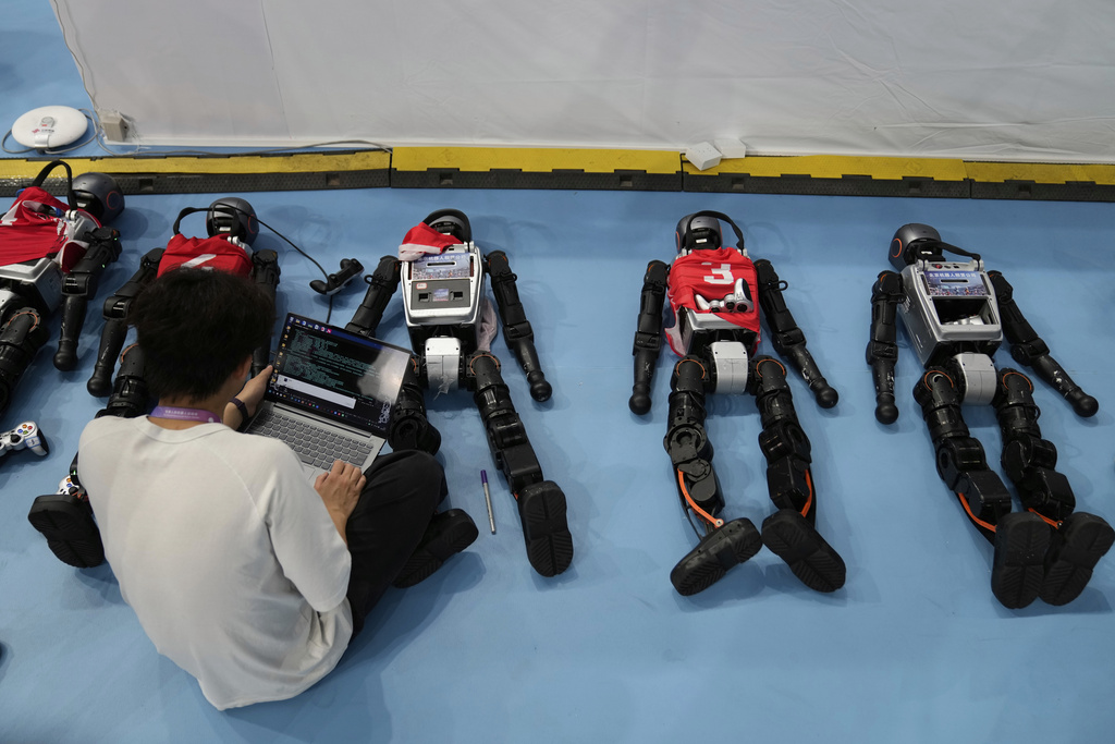 A technicians works on robots during the World Humanoid Robot Games in Beijing, China, Friday, Aug. 15, 2025. (AP Photo/Mahesh Kumar A.)