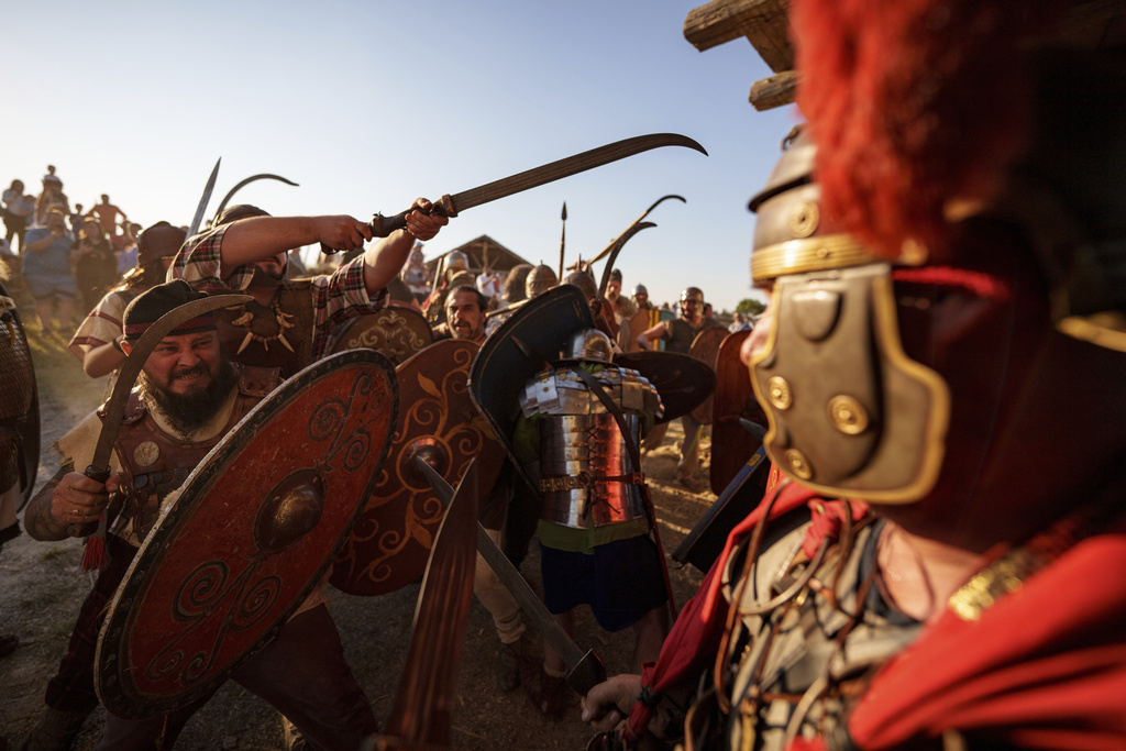 Members of historical reenactment groups wearing Dacian warrior and Roman soldiers outfits, clash in Poiana, Romania, Sunday, July 13, 2025, during the Getodava historical reenactment festival. (AP Photo/Vadim Ghirda)