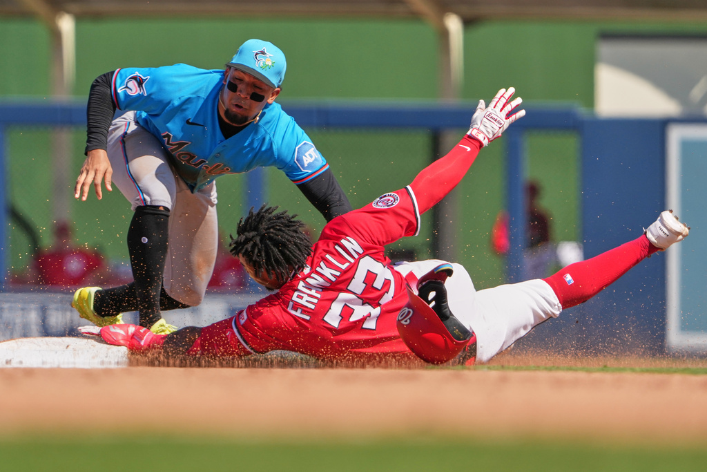 Washington Nationals' Christian Franklin (33) is tagged out by Miami Marlins shortstop Maximo Acosta after trying to stretch a single into a double during the fourth inning of a spring training baseball game Sunday, March 1, 2026, in West Palm Beach, Fla. (AP Photo/Jeff Roberson)