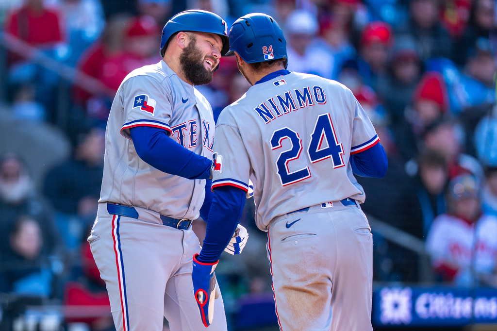 Texas Rangers' Jake Burger, left, celebrates his two-run home run with Brandon Nimmo, right, during the third inning of a baseball game against the Philadelphia Phillies, Saturday, March 28, 2026, in Philadelphia. (AP Photo/Chris Szagola)
