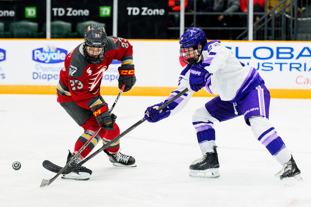 Ottawa Charge's Sarah Wozniewicz (23) losses possession of the puck while being pressured by Minnesota Frost's Natalie Buchbinder (22) during the third period of an PWHL hockey game in Ottawa, Saturday, Jan. 3, 2026. (Spencer Colby/The Canadian Press via AP)