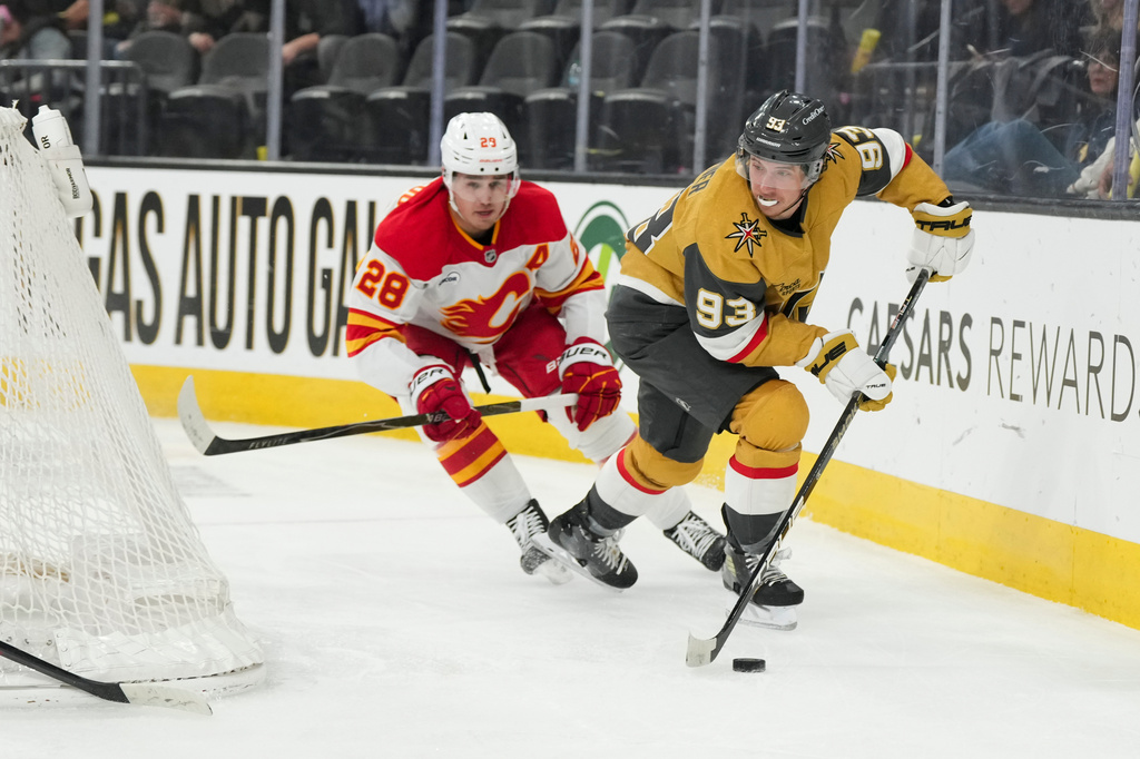 Vegas Golden Knights right wing Mitch Marner (93) skates with the puck against Calgary Flames defenseman Zach Whitecloud (28) during the second period of an NHL hockey game Thursday, April 2, 2026, in Las Vegas. (AP Photo/Candice Ward)