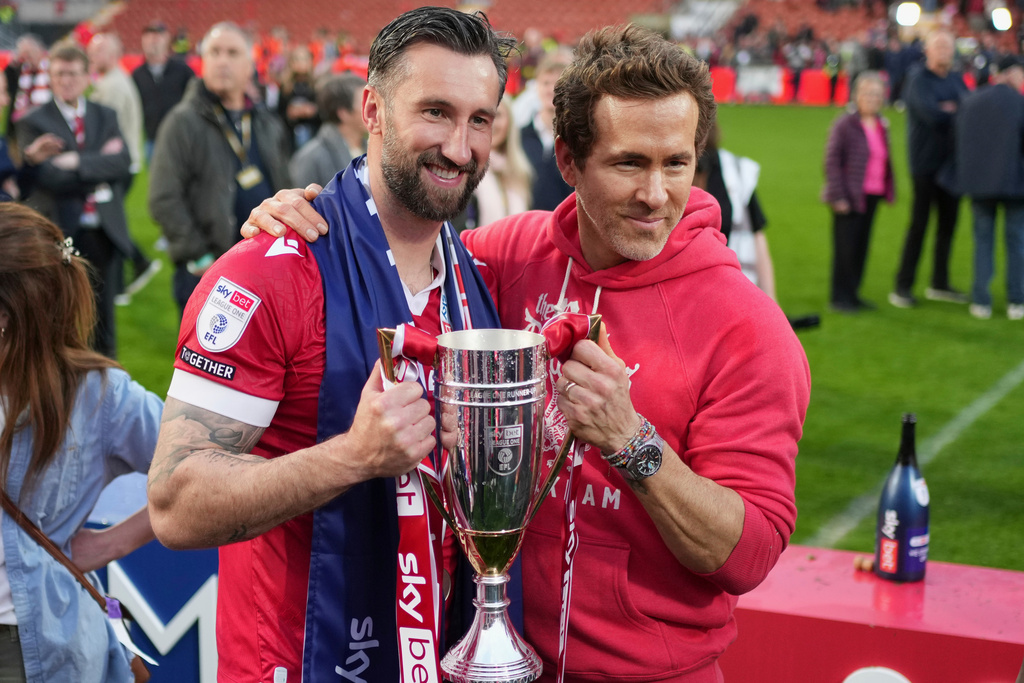 FILE - Wrexham co-owner Ryan Reynolds, right, and Wrexham's Ollie Palmer pose with trophy at the end of the English League One soccer match between Wrexham and Charlton Athletic at the Racecourse ground in Wrexham, Wales, April 26, 2025. (AP Photo/Jon Super, File)