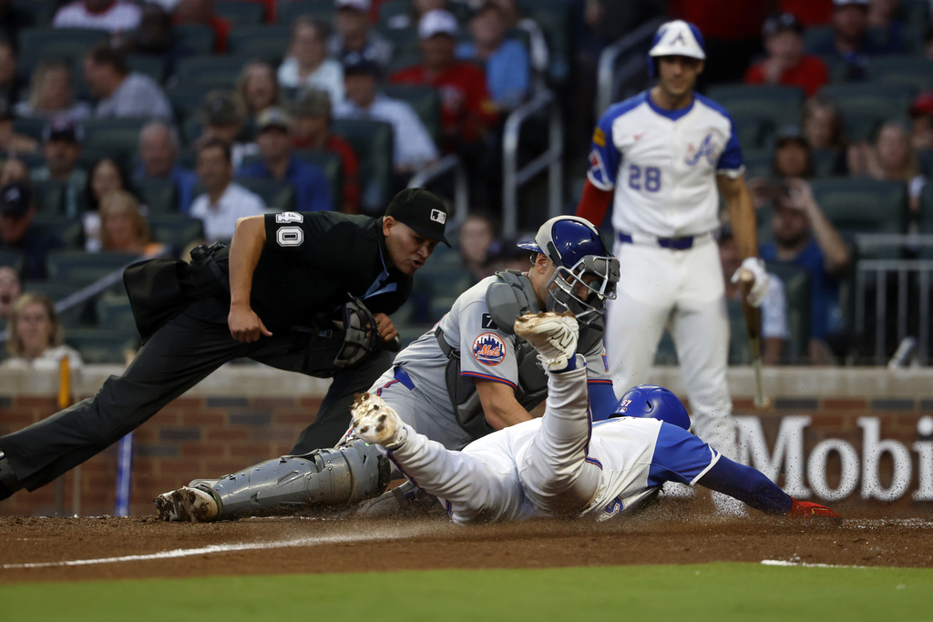 Atlanta Braves' Nacho Alvarez Jr. (67) is tagged out by New York Mets catcher Hayden Senger (30) as he slides into home plate during the third inning of a baseball game, Saturday, Aug. 23, 2025, in Atlanta. (AP Photo/Butch Dill)