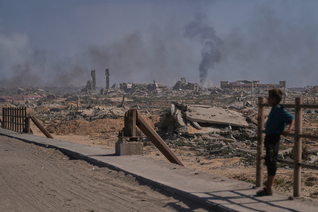 A displaced Palestinian boy looks at smoke rising into the sky following an Israeli military strike in Gaza City, as seen from the central Gaza Strip, Thursday, Oct. 2, 2025. (AP Photo/Abdel Kareem Hana)