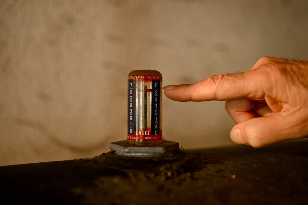 Mark Bain, who is part of the Low Income Home Energy Assistance Program, checks the level on his oil at home in hopes that he will have enough oil to outlast the shutdown, in Bloomfield, Conn., Monday, Oct. 27, 2025. (AP Photo/Jessica Hill)