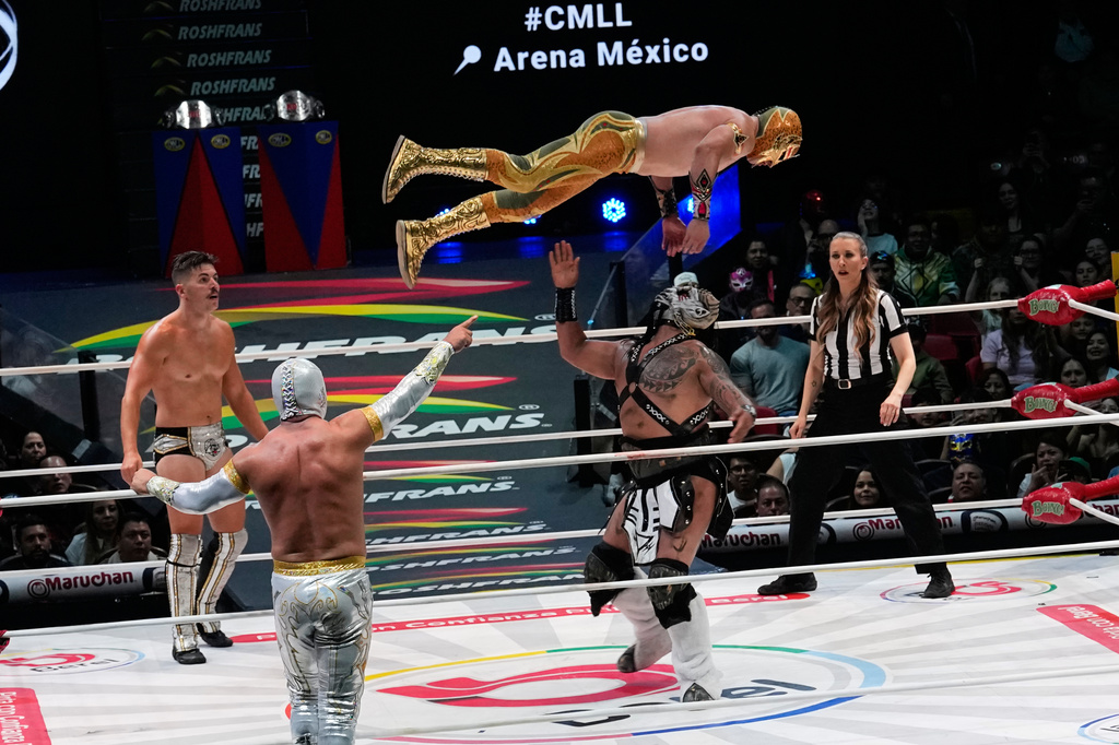 Lucha libre wrestlers Mascara Dorada flies over The Beast Mortos, as Sammy Guevara, left, and Mistico, back to camera, face off at Arena Mexico in Mexico City, Friday, June 26, 2026. (AP Photo/Marco Ugarte)