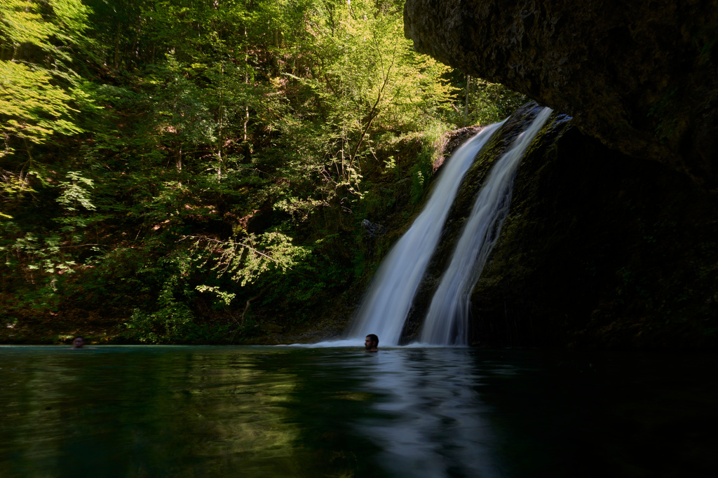People swim beneath a waterfall in the Enipeas Gorge on Mount Olympus in northern Greece, Tuesday, July 14, 2026. (AP Photo/Petros Giannakouris)
