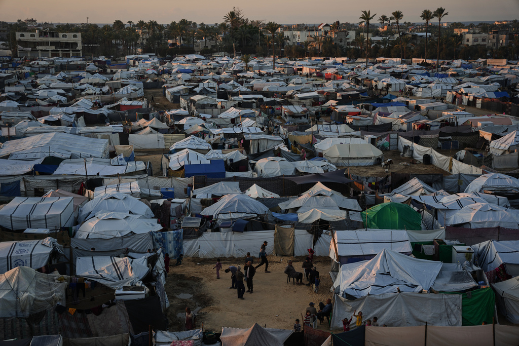 Displaced Palestinians gather outside a tent at a temporary camp in Deir al-Balah, central Gaza Strip, Wednesday, Nov. 26, 2025. (AP Photo/Abdel Kareem Hana)