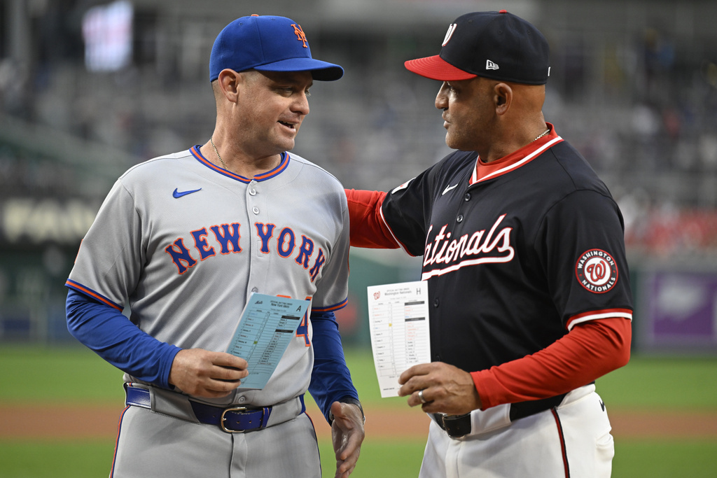 New York Mets manager Carlos Mendoza, and Washington Nationals interim manager Miguel Cairo meet at home plate to exchange lineup cards on Tuesday, Aug. 19, 2025, in Washington. They are the first Venezuelan born managers to face each other in a major league baseball game. (AP Photo/John McDonnell)