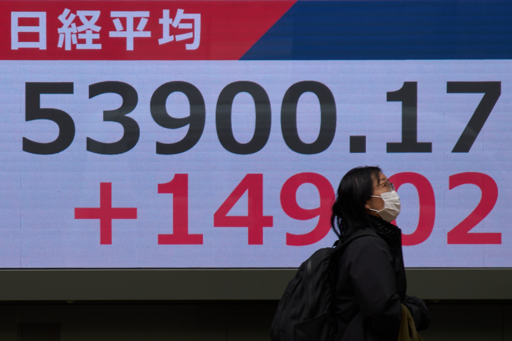 A person walks near a stock price monitor showing Nikkei index at a security company Tuesday, March 17, 2026, in Tokyo. (AP Photo/Eugene Hoshiko)