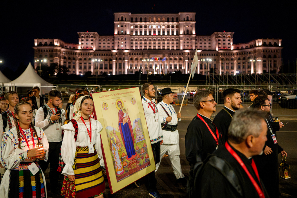 Youngsters wearing traditional outfits carry a religious icon backdropped by the Palace of Parliament during the Procession of Lights, part of a four-day program of the International Meeting of Orthodox Youth (ITO), in Bucharest, Romania, Wednesday, Sept. 2, 2026. (AP Photo/Andreea Alexandru)