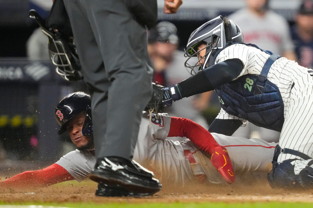 Boston Red Sox' Ceddanne Rafaela is tagged out by New York Yankees catcher Austin Wells at home plate on a double play during the seventh inning of a baseball game, Friday, Aug. 28, 2026, in New York. (AP Photo/Yuki Iwamura)