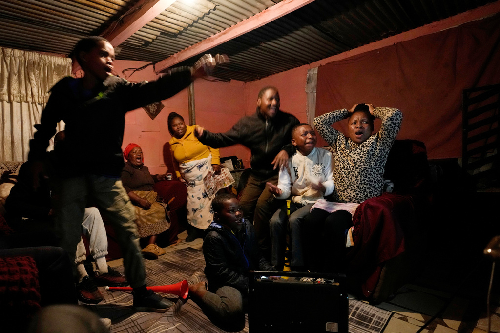 A family watches a world cup opening soccer match, in Vereeniging, South Africa, Thursday, June 11, 2026. (AP Photo/Themba Hadebe)