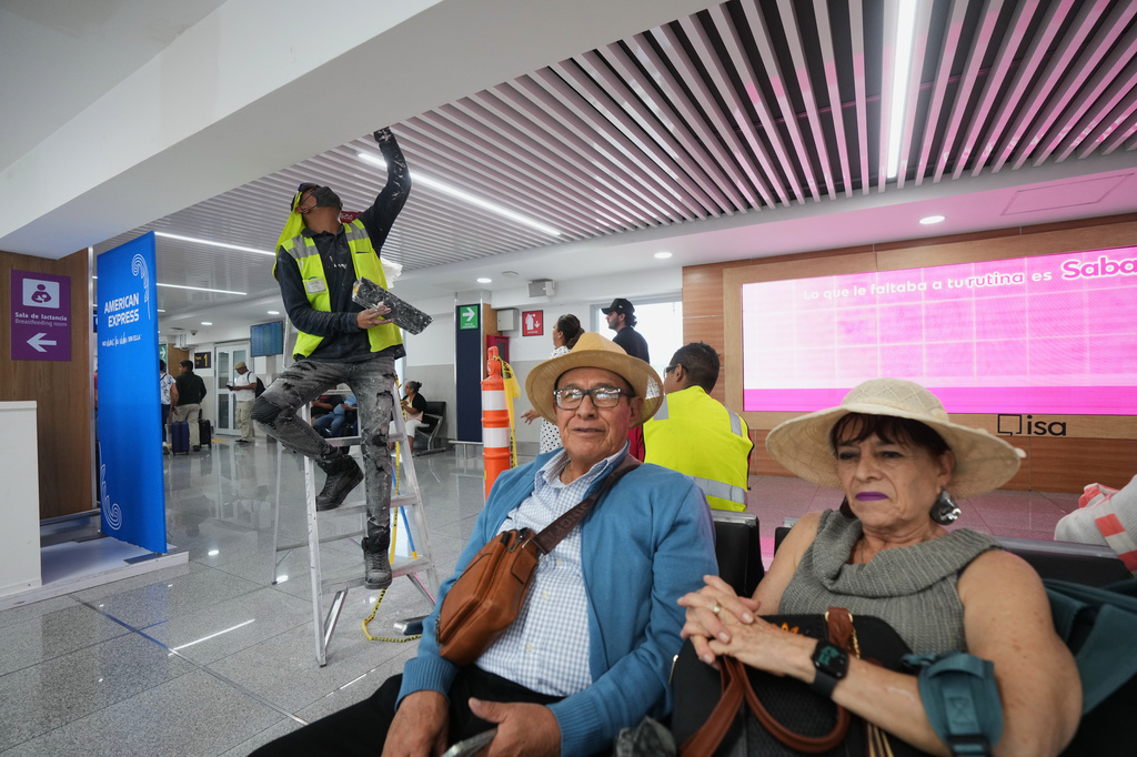 A worker paints the ceiling during a guided media tour of the renovation work at Benito Juárez International Airport, in preparation for the 2026 World Cup, as passengers await their flights in Mexico City, Tuesday, May 19, 2026. (AP Photo/Fernando Llano)