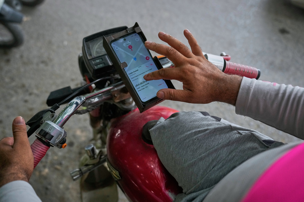 Hamza Ali, 28, who lost both legs in a road accident, uses a mobile app to communicate with a customer for a food delivery order in Islamabad, Pakistan, Friday, July 17, 2026. (AP Photo/Anjum Naveed)