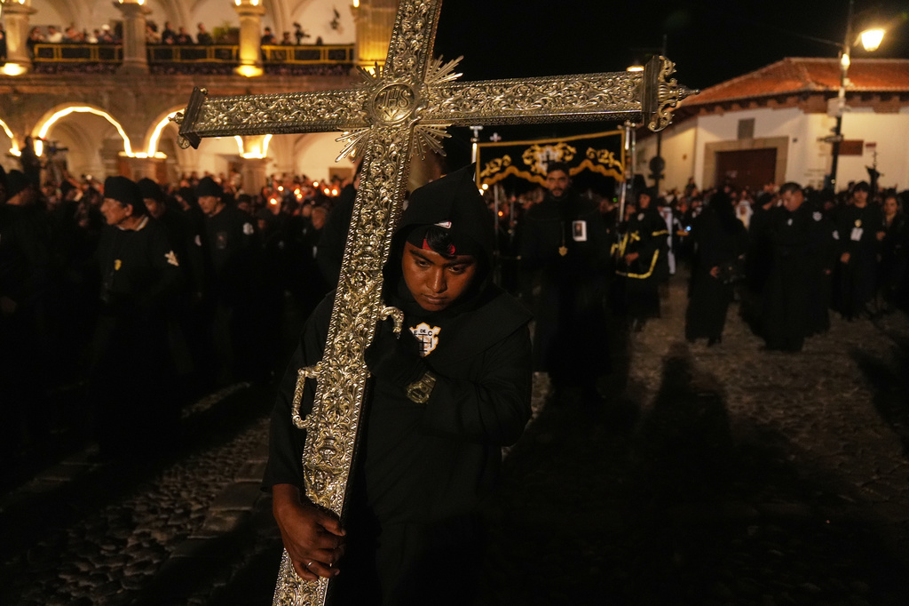A worshiper holds a cross during La Escuela de Cristo church's Good Friday procession during Holy Week in Antigua, Guatemala, Friday, April 3, 2026. (AP Photo/Moises Castillo)