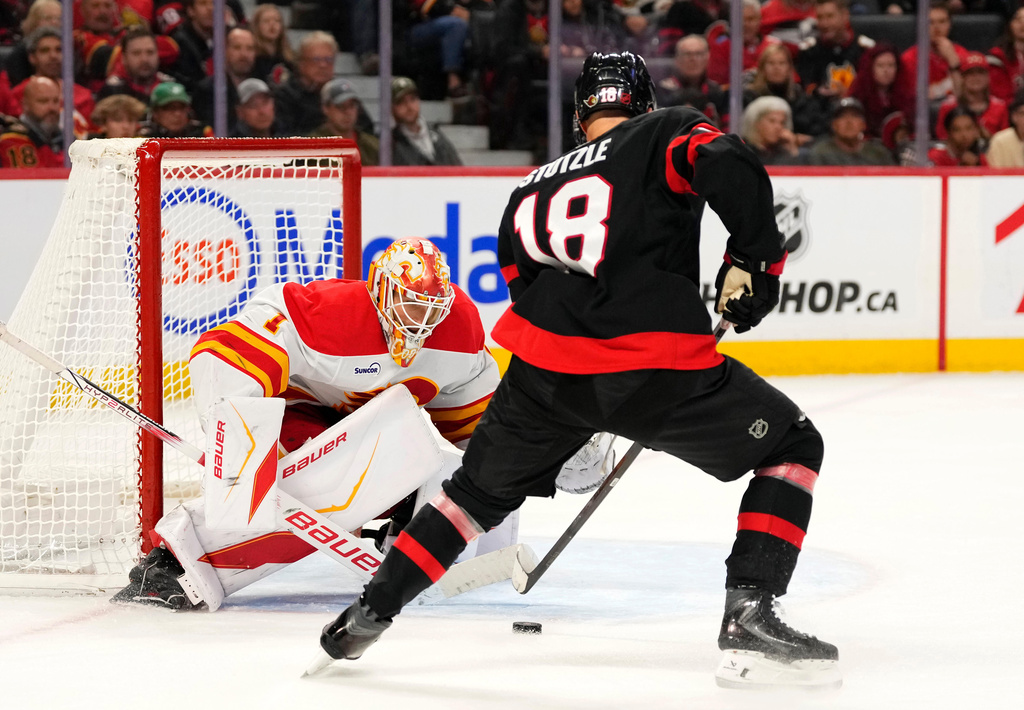 Calgary Flames goaltender Devin Cooley (1) looks to make a save against Ottawa Senators' Tim Stutzle (18) during second period NHL hockey action in Ottawa, on Thursday, Oct. 30, 2025. (Justin Tang/The Canadian Press via AP)