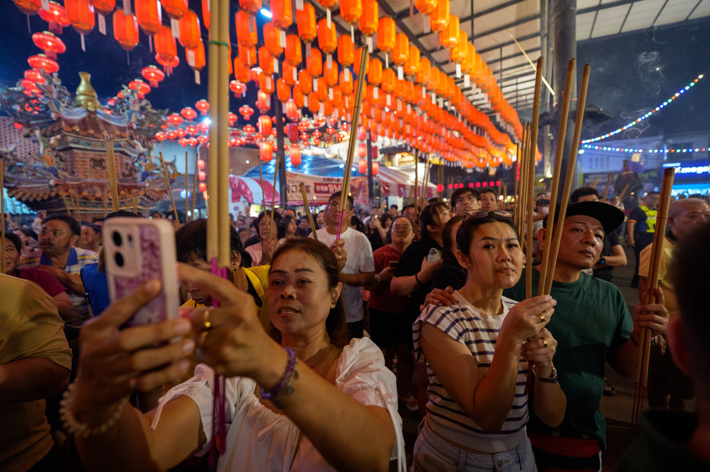 Ethnic Chinese devotees hold incense sticks as they watch a procession during the Hungry Ghost Festival in Bukit Metajam, Malaysia, Saturday, Aug. 29, 2026. (AP Photo/Vincent Thian)