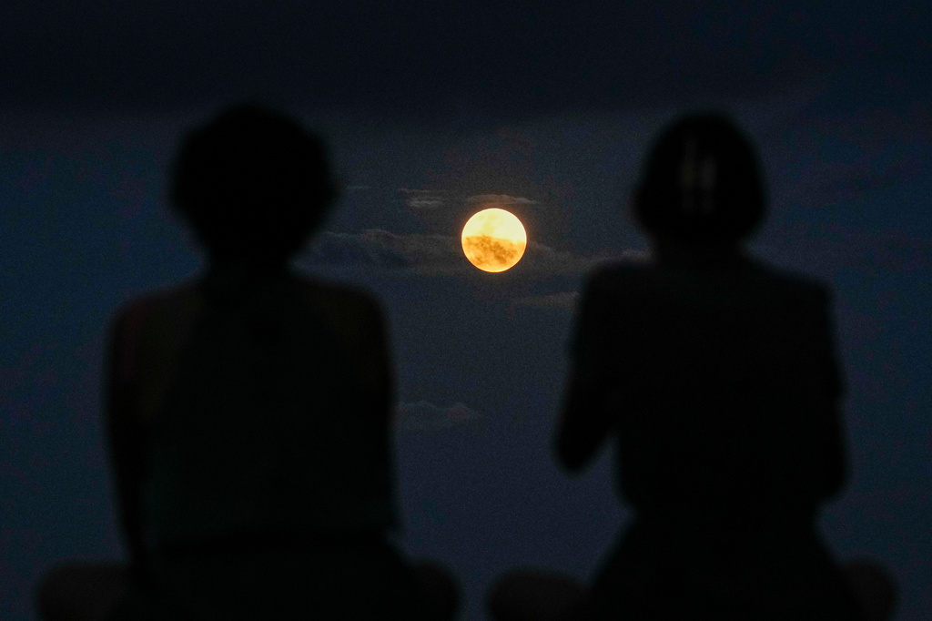 FILE - The full moon rises behind a couple, in Panama City, April 1, 2026. (AP Photo/Matias Delacroix, File)