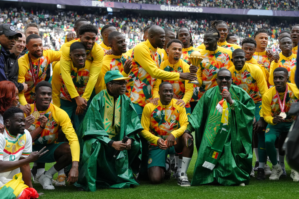 Singer Youssou N'dour, bottom row third left, celebrates with the Senegal team ahead of the international friendly soccer match between Senegal and Peru in Saint-Denis, outside of Paris, Saturday, March 28, 2026. (AP Photo/Aurelien Morissard)