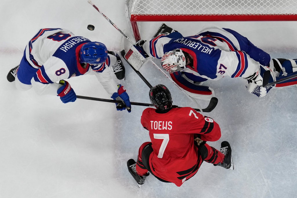 Canada's Devon Toews (7) challenges with United States' Zach Werenski (8) during a men's ice hockey gold medal game between Canada and the United States at the 2026 Winter Olympics, in Milan, Italy, Sunday, Feb. 22, 2026. (AP Photo/Petr David Josek)