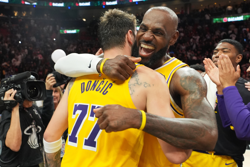 Los Angeles Lakers guard Luka Doncic (77) and forward LeBron James, right, embrace after defeating the Miami Heat in an NBA basketball game, Thursday, March 19, 2026, in Miami. (AP Photo/Lynne Sladky)