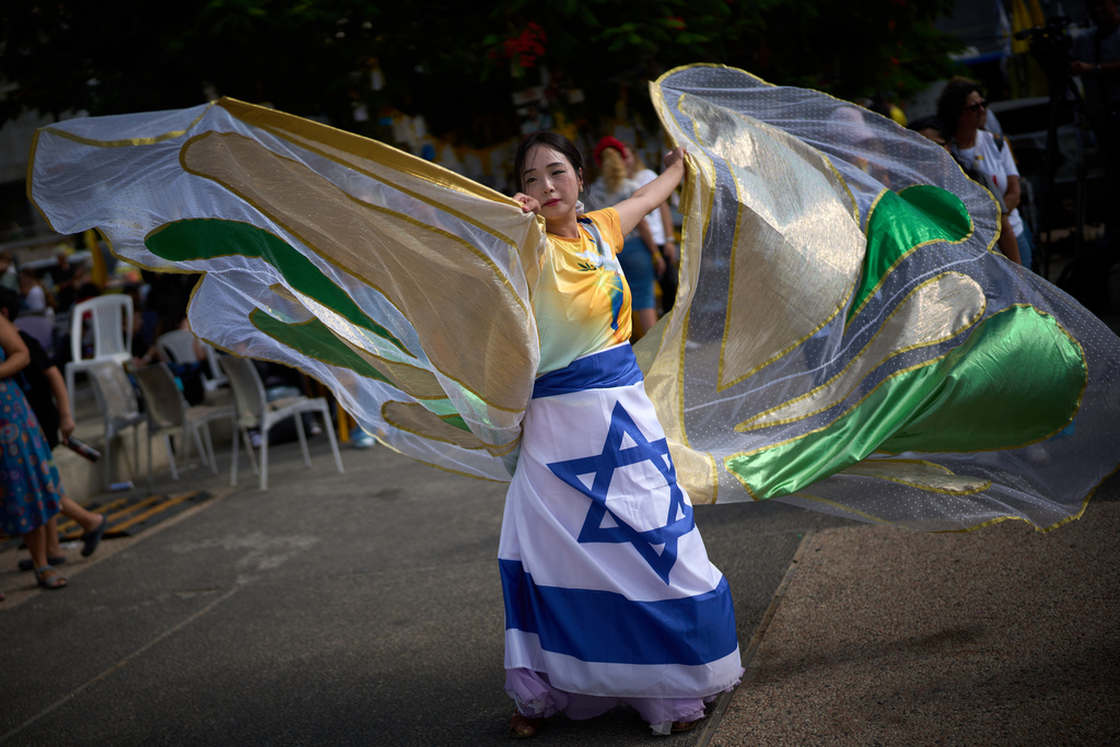 A dancer performs as people gather at a plaza known as hostages square, in Tel Aviv, Israel, Sunday, Oct. 12, 2025. (AP Photo/Emilio Morenatti)
