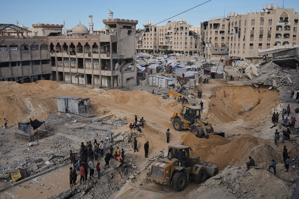 Palestinians watch members of the Hamas militant group searching for bodies of the hostages in an area in Hamad City, Khan Younis, in the southern Gaza Strip, Saturday, Oct. 18, 2025. (AP Photo/Jehad Alshrafi)