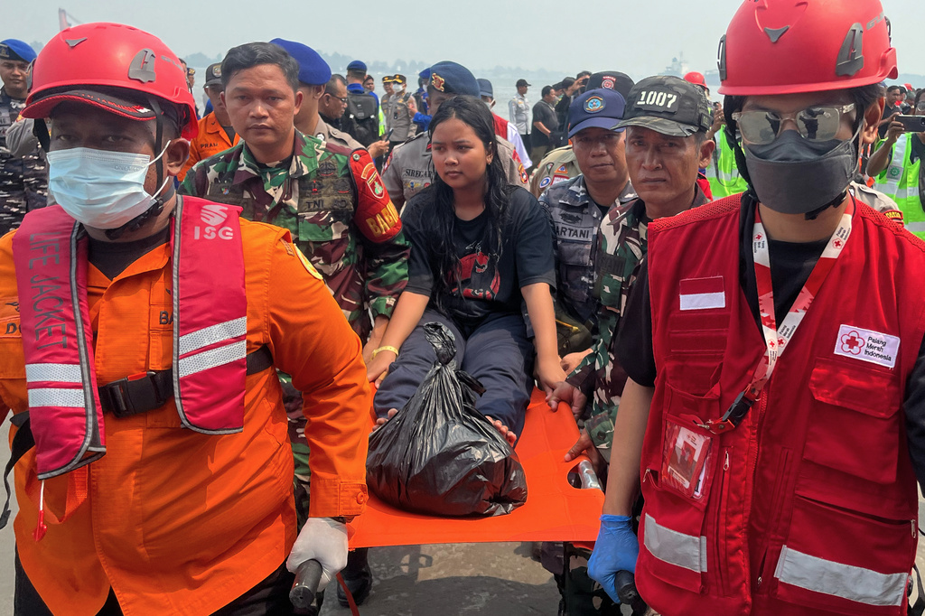 In this photo taken with a smartphone, rescuers carry a survivor from a passenger ferry overturned in bad weather in the Java Sea on a stretcher upon arrival at a port in Banjarmasin, South Kalimantan, Indonesia, Tuesday, Sept. 15, 2026. (AP Photo/Iman Satria)