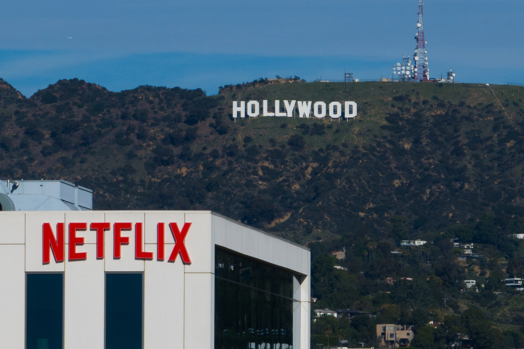 A Netflix sign is displayed atop a building in Los Angeles, Thursday, Dec. 18, 2025, with the Hollywood sign in the distance. (AP Photo/Jae C. Hong)