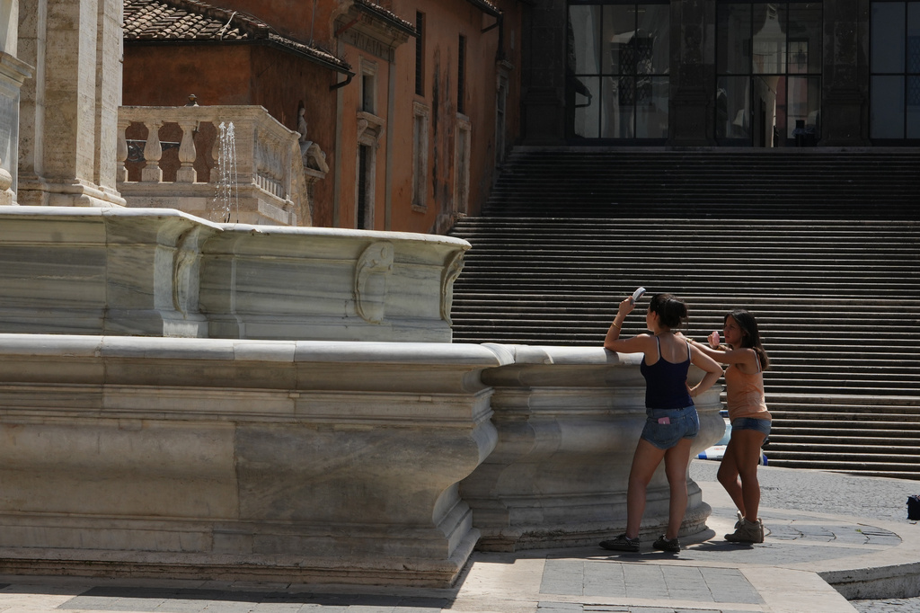 Tourists use handheld fans as they pause in Piazza del Campidoglio on Rome's Capitoline Hill, Saturday, Aug. 1, 2026. (AP Photo/Alessandra Tarantino)