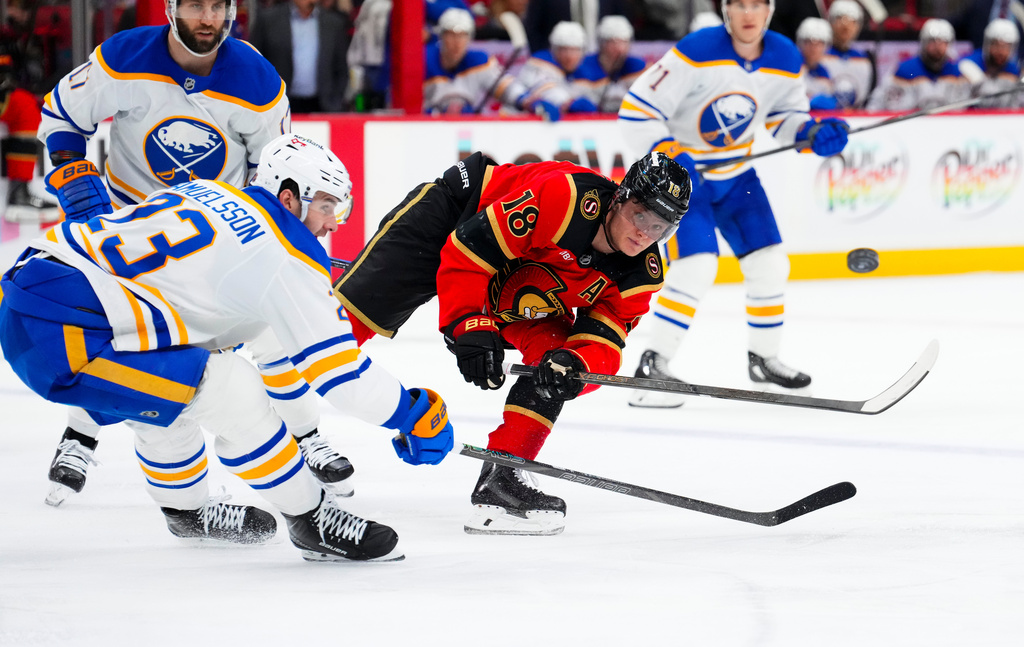 Ottawa Senators' Tim Stutzle (18) passes the puck around Buffalo Sabres' Mattias Samuelsson (23) during the second period of an NHL hockey game in Ottawa on Thursday, April 2, 2026. (Sean Kilpatrick/The Canadian Press via AP)