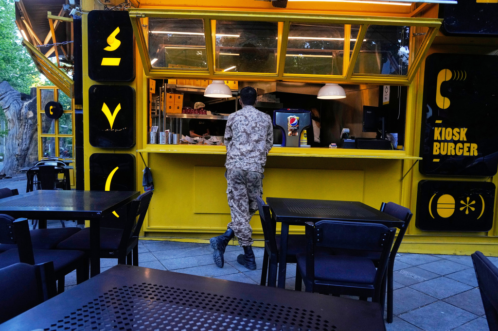 A Revolutionary Guard soldier stands at the counter of a fast food restaurant in northern Tehran, Iran, Sunday, May 10, 2026. (AP Photo/Vahid Salemi)