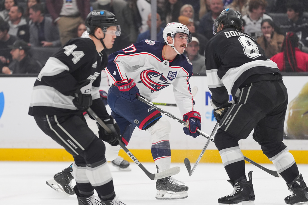 Columbus Blue Jackets's Mason Marchment (17) hits the puck under defense by Los Angeles Kings' Drew Doughty (8) during the first period of an NHL hockey game Monday, Dec. 22, 2025, in Los Angeles. (AP Photo/Jae C. Hong)