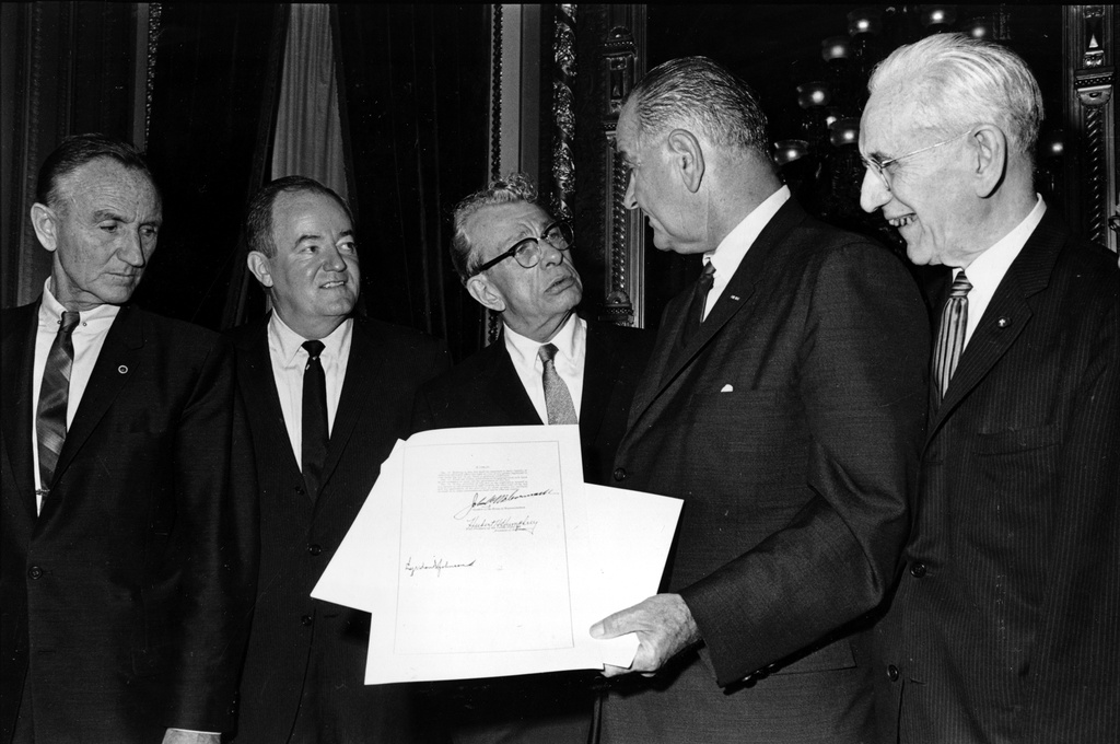 FILE - President Lyndon B. Johnson holds the signed document of the Voting Rights Act of 1965 as he chats with Sen. Everett Dirksen, R-Ill., in the President's Room in Washington, Aug. 6, 1965. Signatures that appear on the document are Johnson, left bottom; House Speaker John McCormack, upper, standing at right; and Vice President Hubert Humphrey, lower, standing second from left. Standing at far left is Sen. Mike Mansfield. (AP Photo)