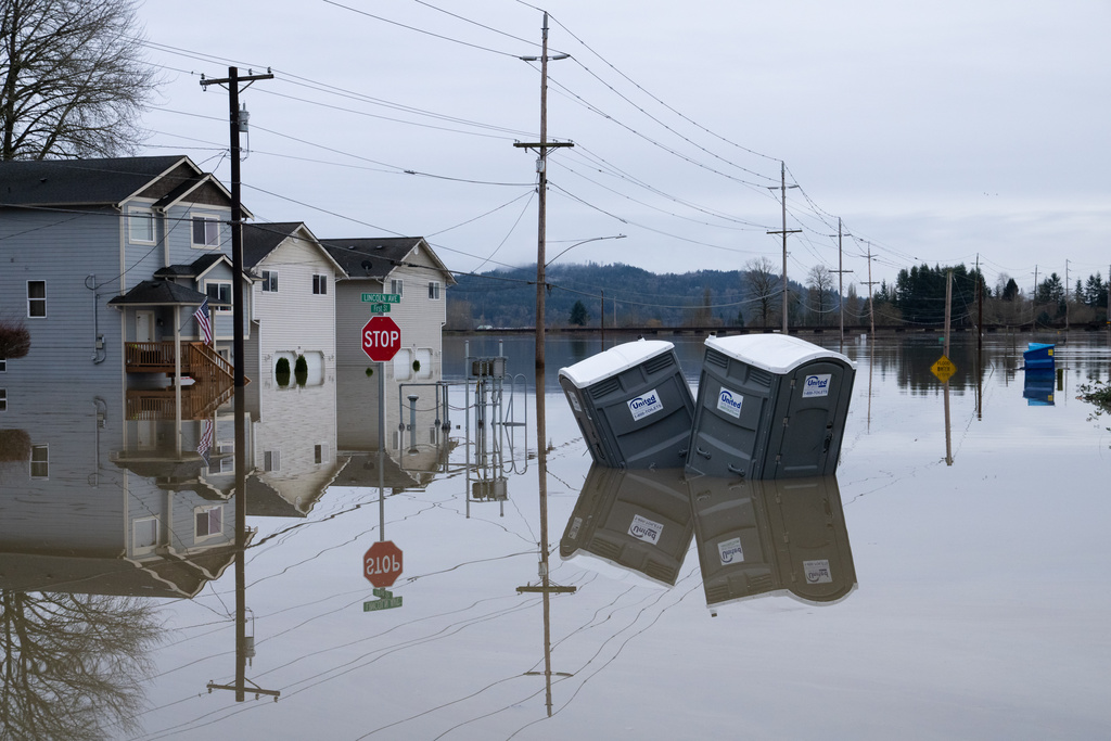 Partially inundated residences and portable toilets sit in floodwaters in Snohomish, Wash., Thursday, Dec. 11, 2025. (AP Photo/Stephen Brashear)