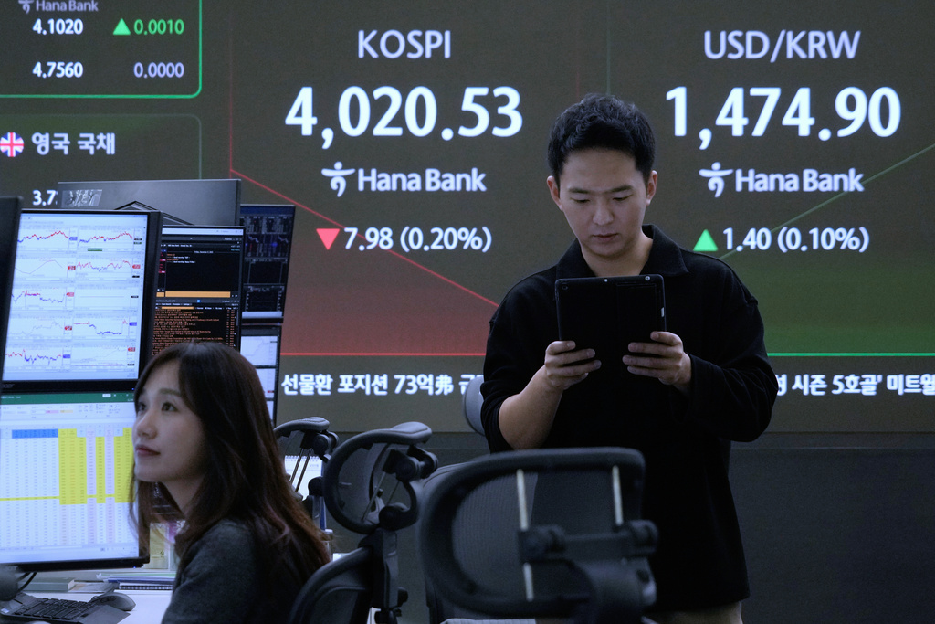 Currency traders work near a screen showing the Korea Composite Stock Price Index (KOSPI) and the foreign exchange rate between U.S. dollar and South Korean won, top right, at the foreign exchange dealing room of the Hana Bank headquarters, in Seoul, South Korea, Friday, Dec. 5, 2025. (AP Photo/Ahn Young-joon)