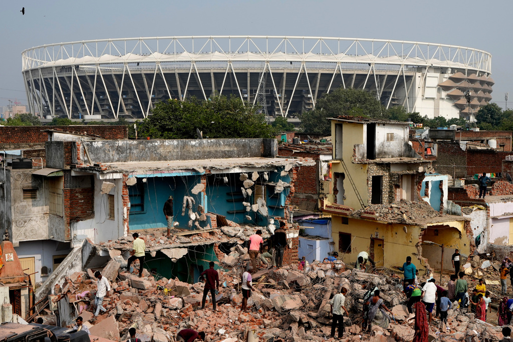 FILE - People search in the rubble after authorities demolished various structures near the Narendra Modi stadium, seen behind, as part of the preparations for the 2030 Commonwealth Games in Ahmedabad, India, Saturday, Nov. 29, 2025. (AP Photo/Ajit Solanki,File)